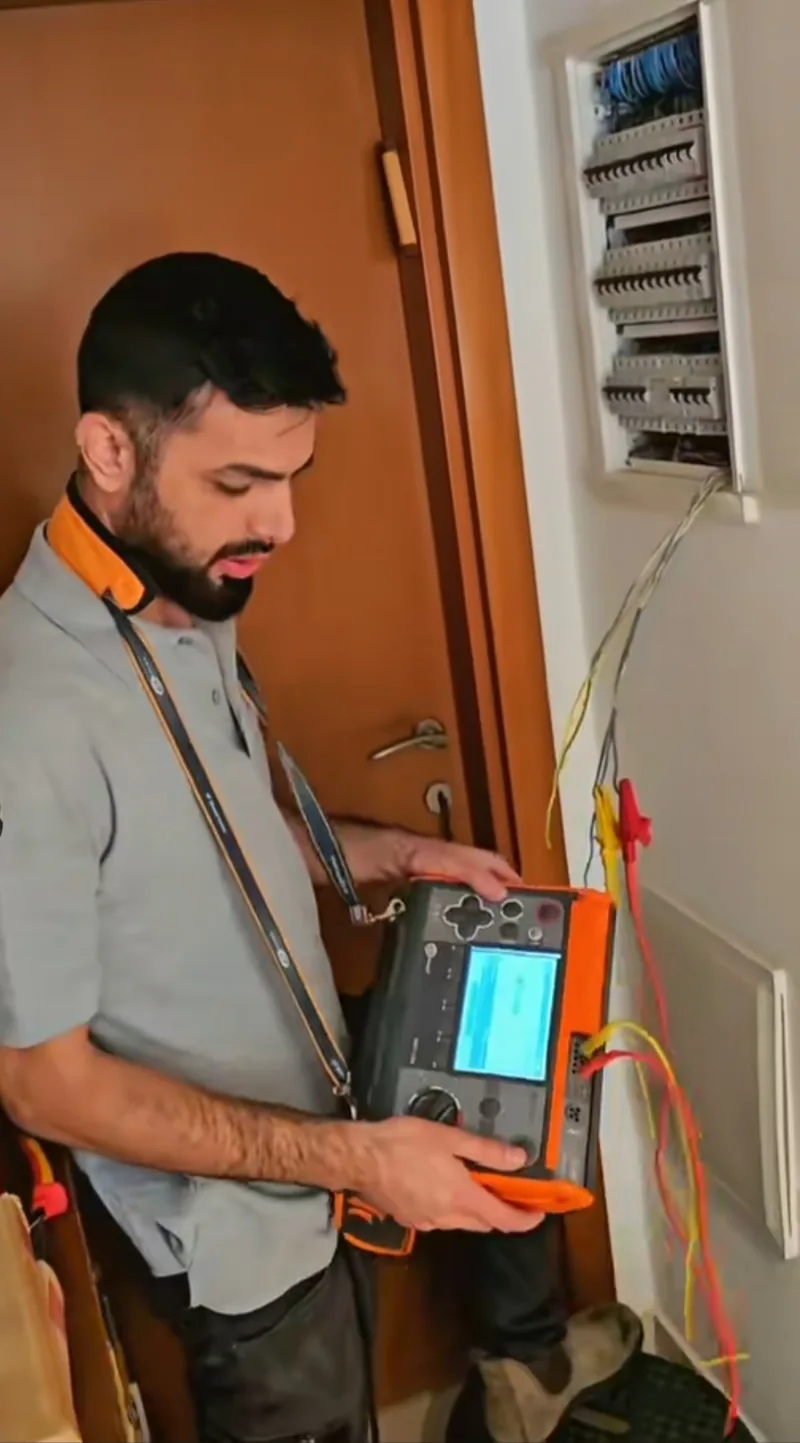 יהודה חכמוב מבצע בדיקת בידוד במכשיר מדידה המחובר ללוח חשמל ביתי פתוח
